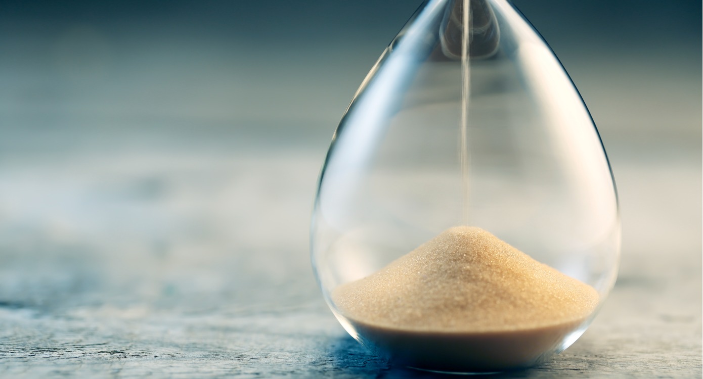 Hourglass with sand pouring while placed on solid ground representing the idea that it's time to add TikTok to your marketing strategy.